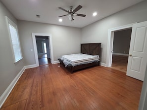 A bedroom with hardwood flooring, a bed, a ceiling fan, and a door leading to another room. - Gated 3,600 Sq. Ft. Luxury Home on 15 acres by Hyundai with 2 car garage (Montgomery)