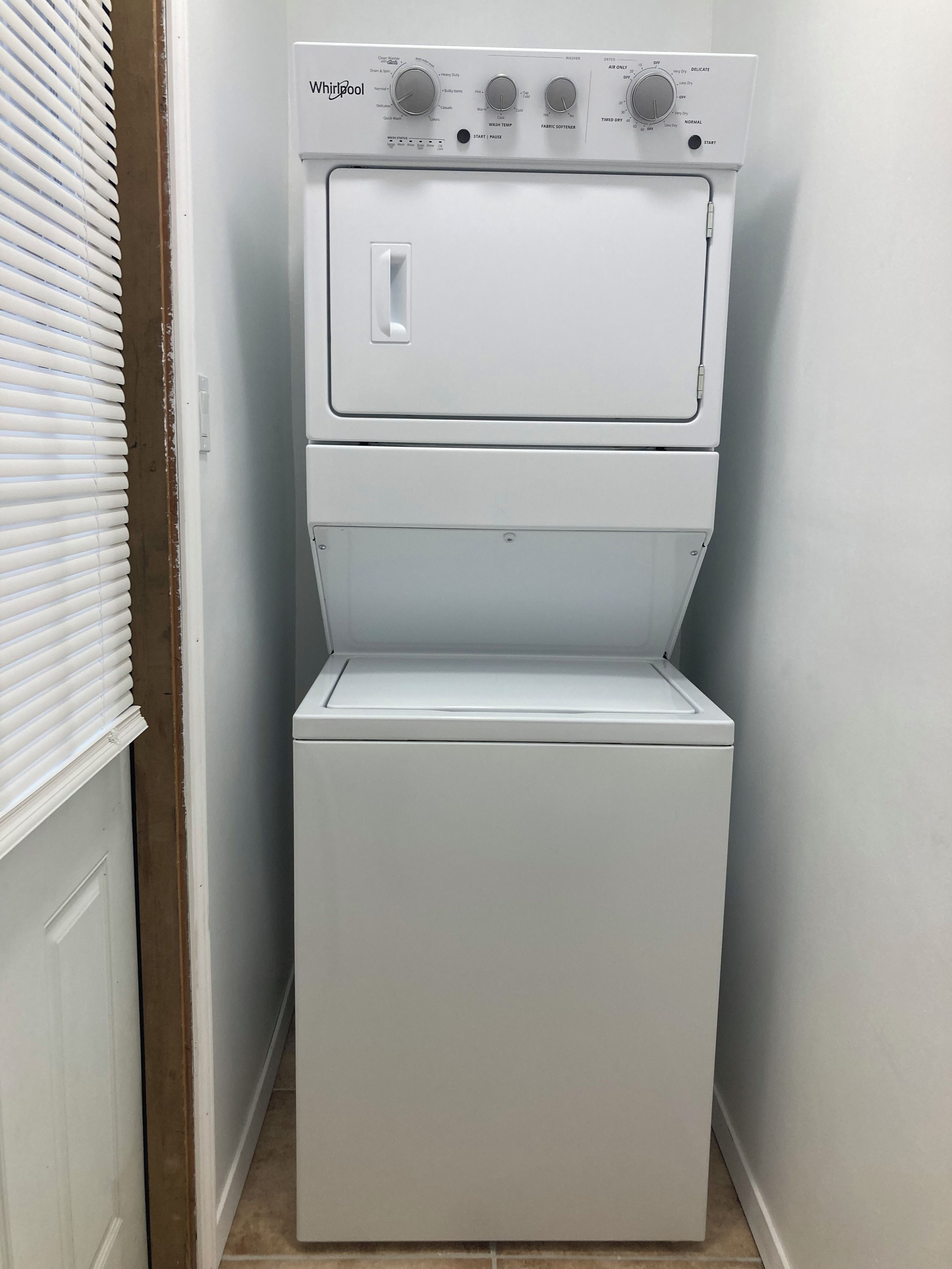 A white Whirlpool washer and dryer unit with control knobs and a start/pause button.