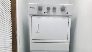 A white Whirlpool washer and dryer unit with control knobs and a start/pause button.