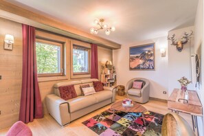 Ein gemütliches Wohnzimmer mit einer Couch, einem Sessel, einem Couchtisch und einem farbenfrohen Teppich.