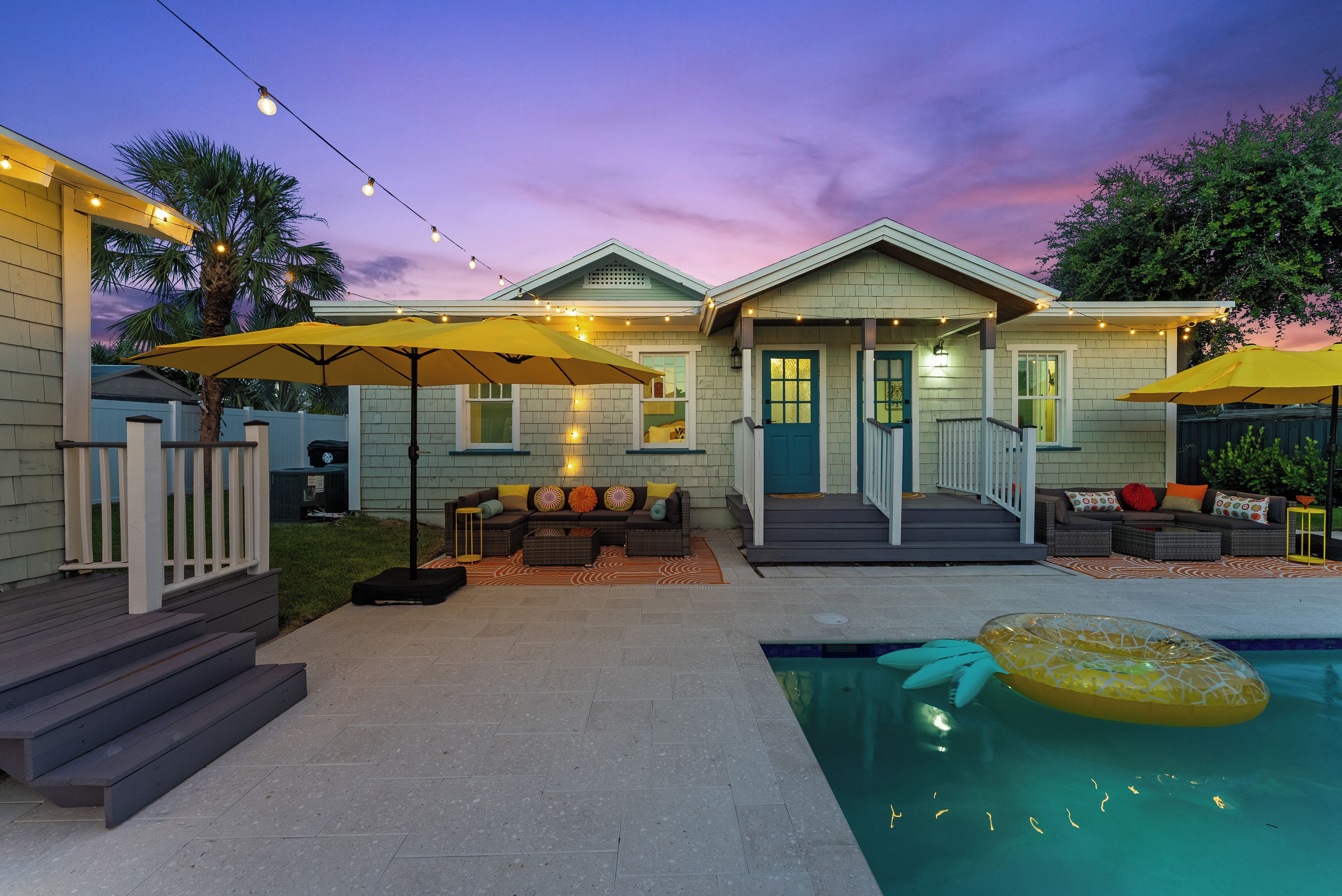 A residential property with a pool, outdoor seating, and string lights.