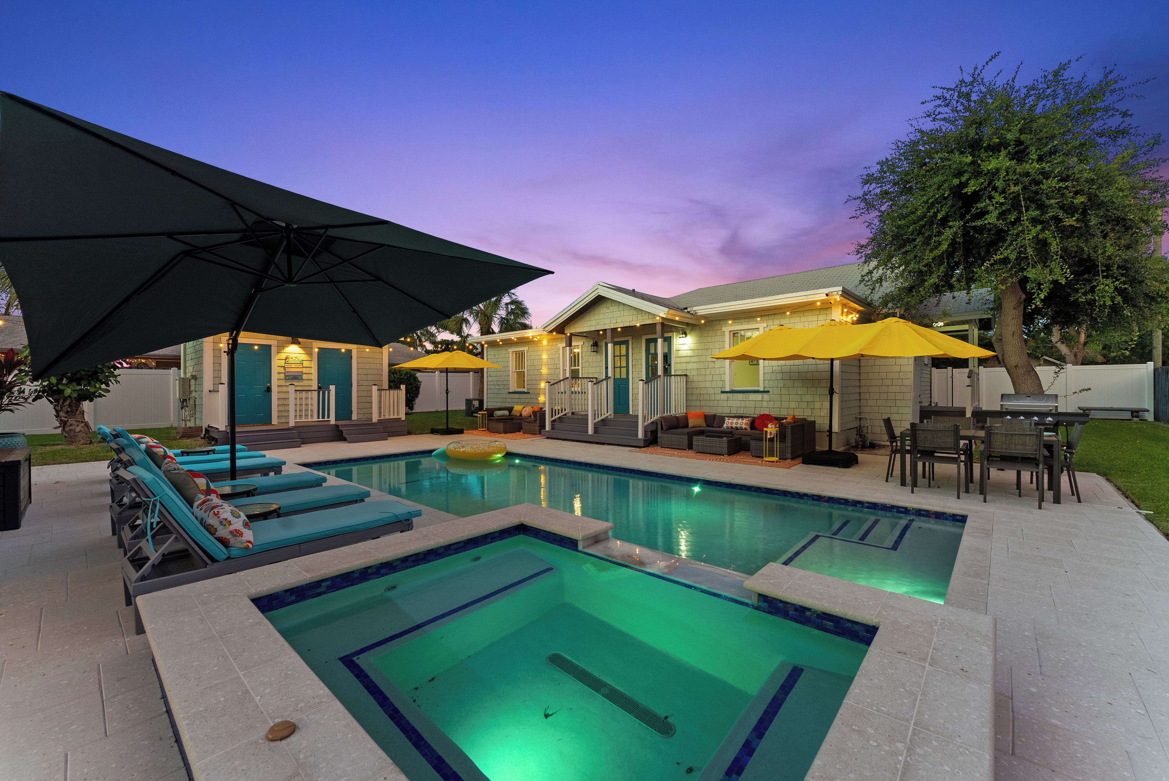 Un patio trasero con piscina, mobiliario exterior y sombrillas.