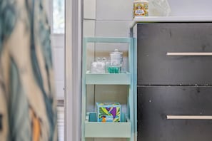 Un baño con un mueble blanco, un estante con una caja y un adorno.