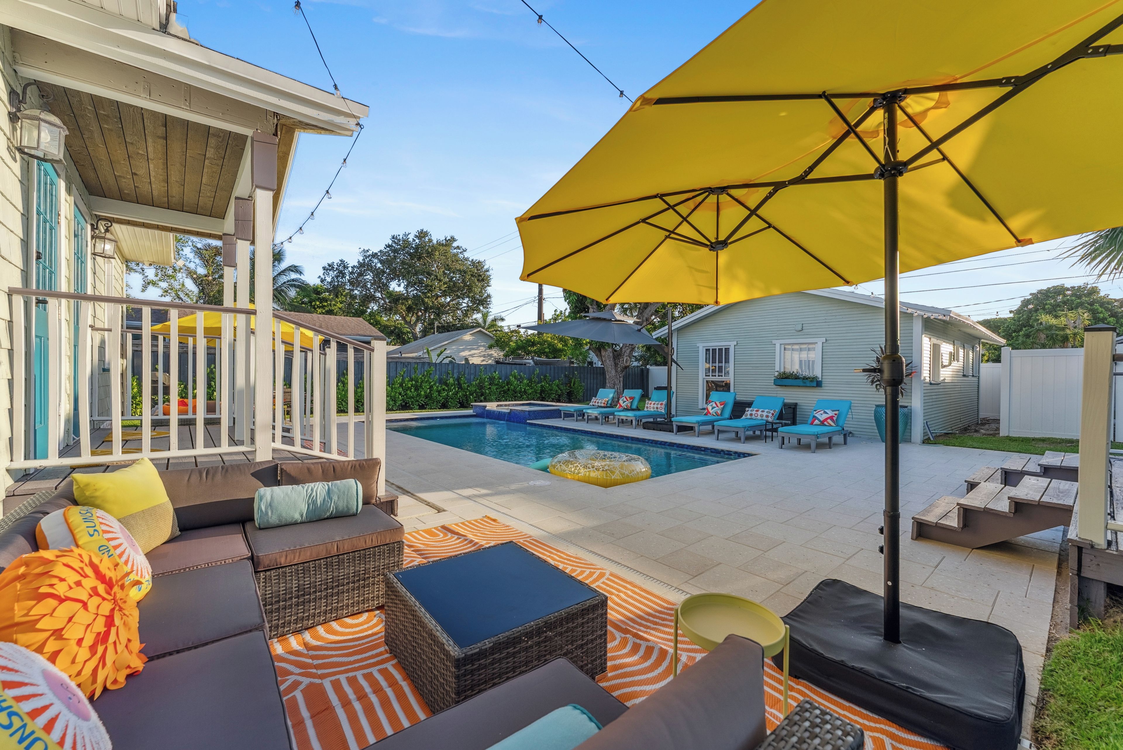 Un jardin avec une piscine, du mobilier d’extérieur et un patio couvert.
