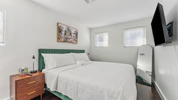 A bedroom with a bed, a bedside table, a mirror, and a painting on the wall.