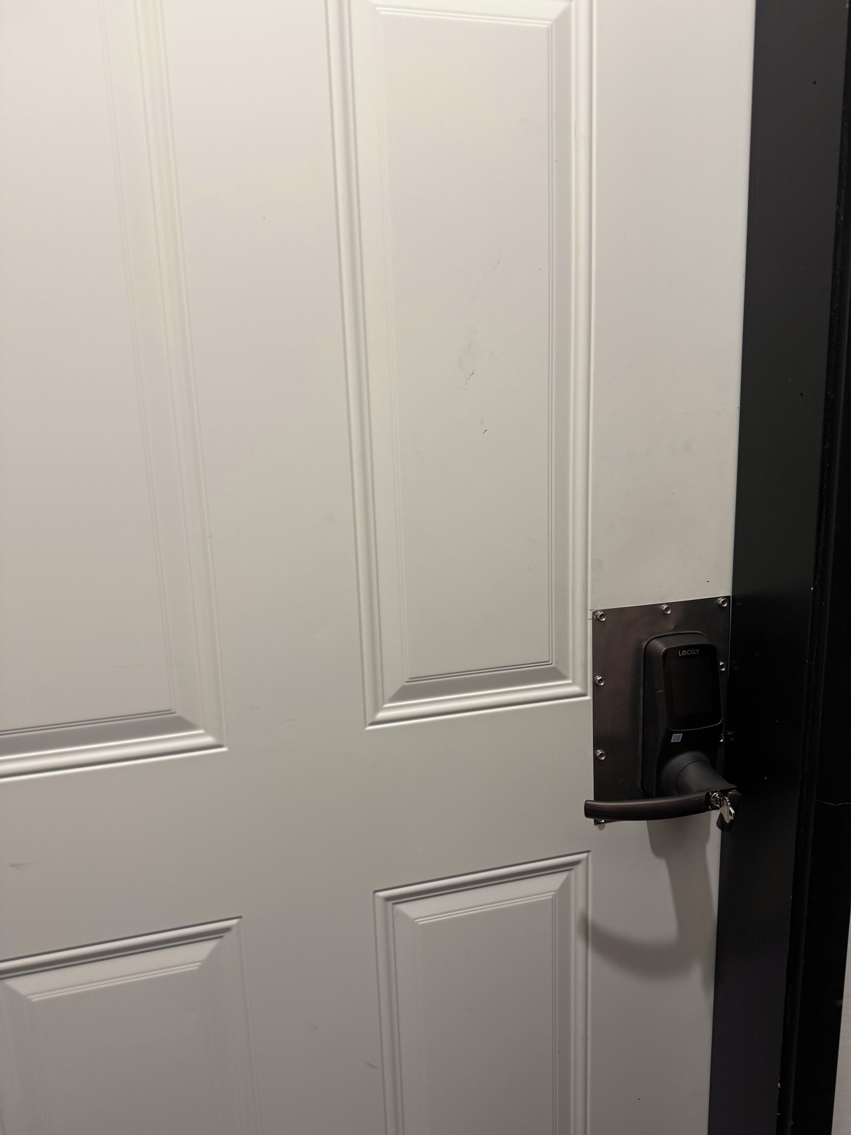 Una porta bianca con maniglia nera e una serratura, dal design semplice ed elegante.
