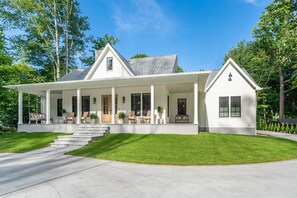 A two-story house with a covered porch, a front entrance, and a driveway. - Luxury-private pool-across from beach (South Haven)