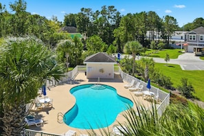 A swimming pool with a deck area, surrounded by a fence, and a small building with a sign. - Footprints on the Fairway , 2BR Beach & Golf with Pool (Little River)