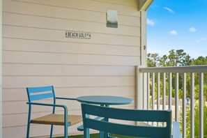 A balcony with a table and chairs, a sign reading 'Beach Golf Dr', and a view of trees and sky. - Footprints on the Fairway , 2BR Beach & Golf with Pool (Little River)