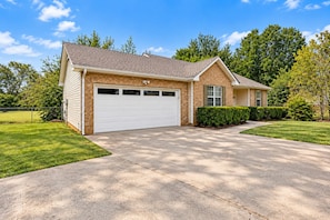 Une maison à deux étages avec un garage, une allée et une pelouse bien entretenue.