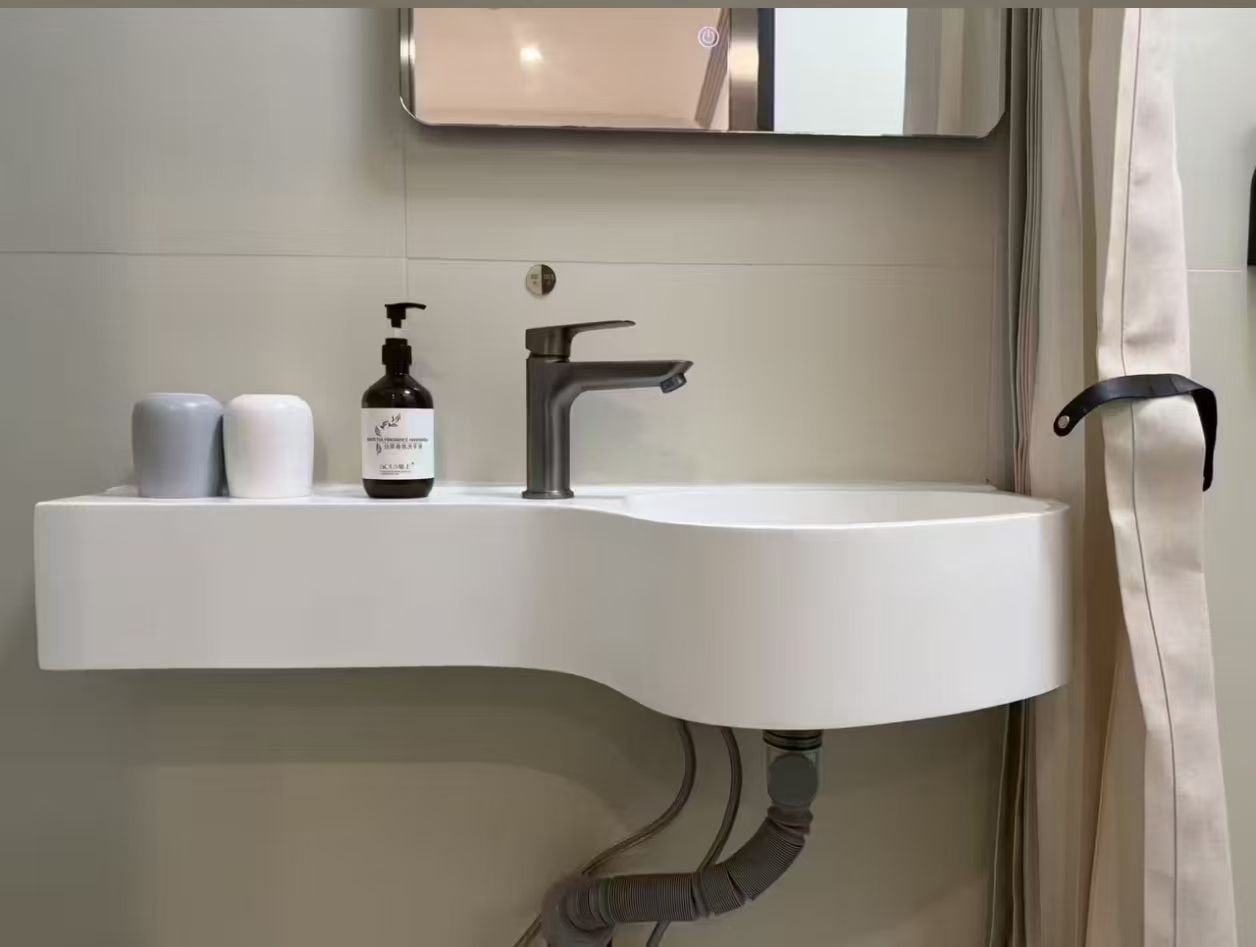 A modern bathroom with a white sink, a faucet, and a bottle of hand soap.