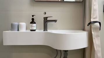 A modern bathroom with a white sink, a faucet, and a bottle of hand soap.