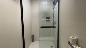 A modern bathroom with a glass-enclosed shower, a toilet, and a towel rack.