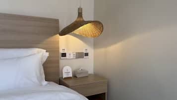 A hotel room with a bed, a bedside table with a lamp, and a wall-mounted charging station.