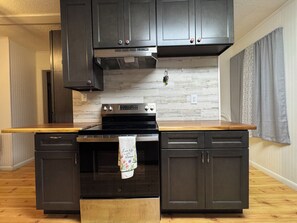 A kitchen with dark cabinets, a stainless steel stove, and a wooden countertop. - Spacious 6-bedroom house in Walhalla, central to all the area attractions (Walhalla)