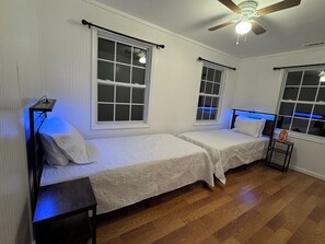 A room with two single beds, a ceiling fan, and a nightstand with a lantern. - Spacious 6-bedroom house in Walhalla, central to all the area attractions (Walhalla)