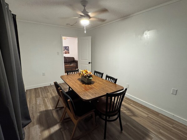 A dining area with a wooden table and chairs, a ceiling fan, and a door leading to another room. - Spacious 6-bedroom house in Walhalla, central to all the area attractions (Walhalla)