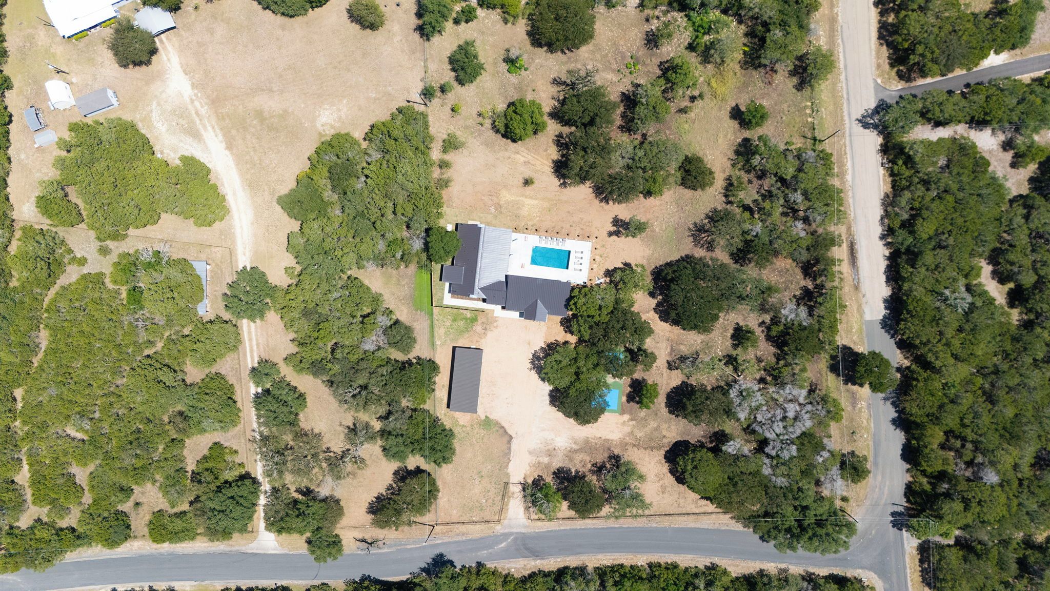 Vista aérea de una propiedad residencial con piscina, garaje independiente y un amplio jardín.