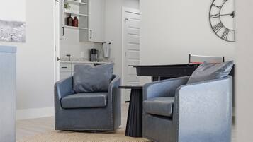 A modern living room with two grey armchairs, a coffee table, and a wall clock.