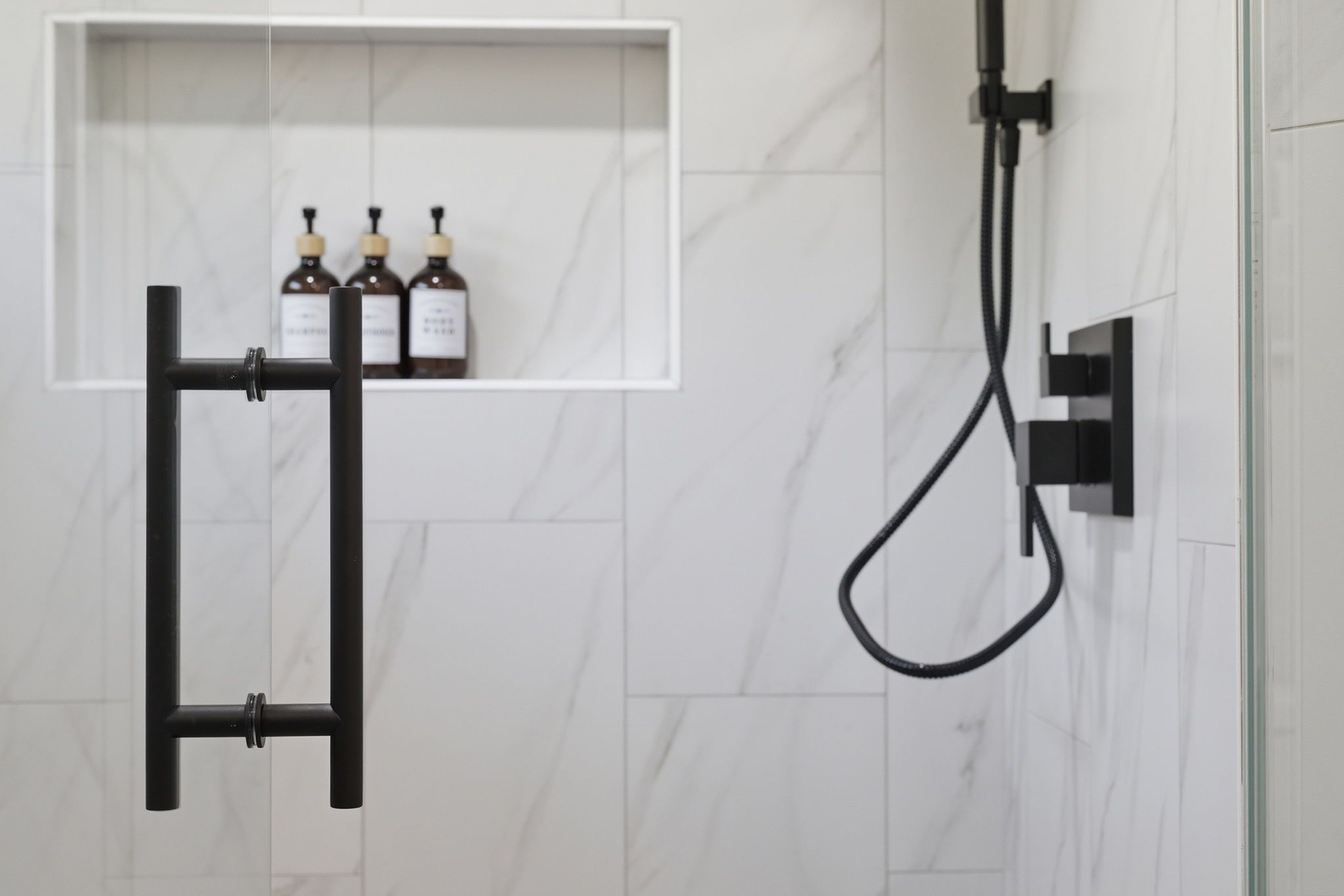A bathroom with a shower, a towel rack, and a shelf with bottles.