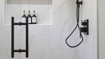 A bathroom with a shower, a towel rack, and a shelf with bottles.