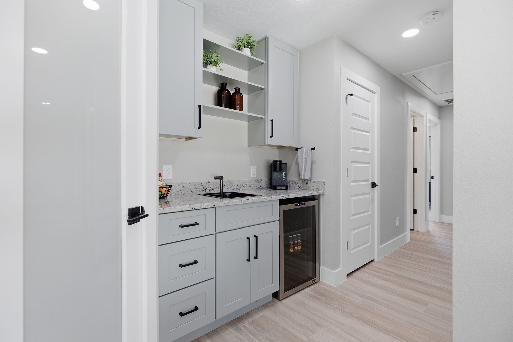 A modern kitchen with white cabinetry, a built-in dishwasher, and a coffee maker.