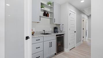 A modern kitchen with white cabinetry, a built-in dishwasher, and a coffee maker.