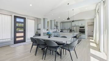 Une cuisine moderne dotée d’un îlot central, de meubles de couleur grise et d’un coin repas avec des chaises.