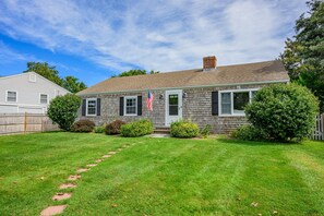 A single-story house with a front porch, a chimney, and a small front yard with a lawn and bushes. - Ripple Effect - near the beach and Main Street (Hyannis)