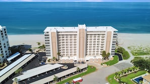 Ein mehrstöckiges Hotel mit Blick auf den Strand, Parkmöglichkeiten und einem überdachten Außenbereich.