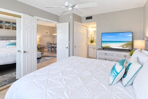 Ein Hotelzimmer mit einem großen Bett, einem Fernseher und Blick auf den Strand.