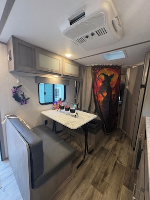 Cocina compacta para autocaravana con kitchenette, comedor y un pequeño espacio para sentarse.