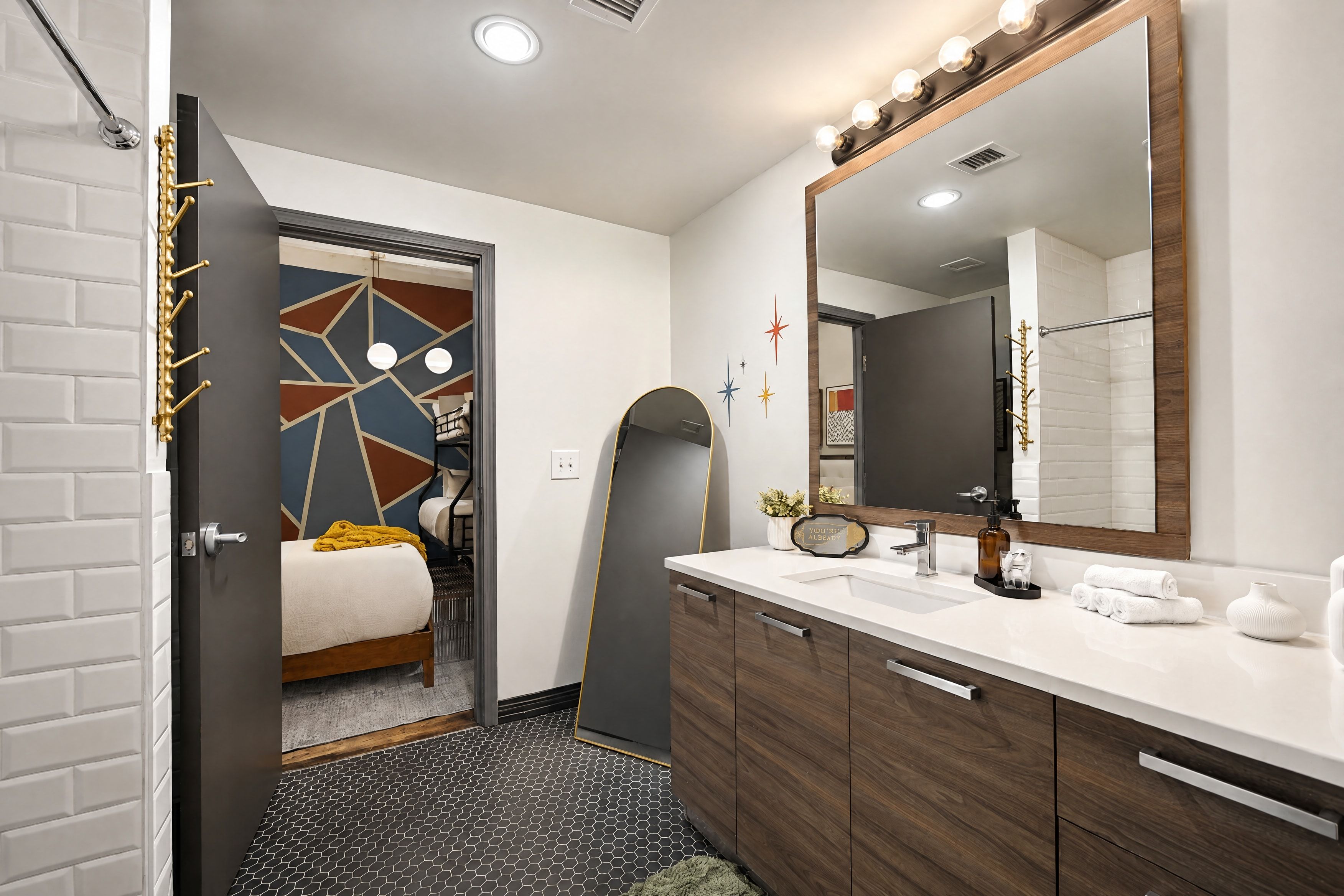 A modern bathroom with a large mirror, white sink, and wooden vanity.