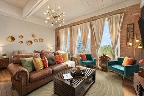Un salon moderne avec un canapé en cuir, des fauteuils turquoise et une table basse en bois.