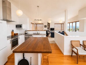Une cuisine moderne dotée d’un îlot central, de meubles blancs et d’un plancher en bois.