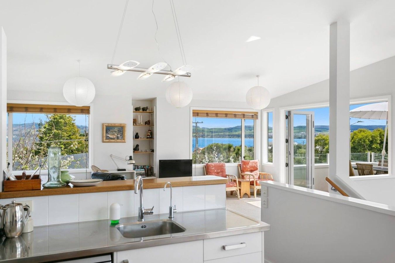 A modern kitchen with a large window, a dining area with a view, and a balcony with outdoor seating.