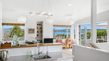 A modern kitchen with a large window, a dining area with a view, and a balcony with outdoor seating.