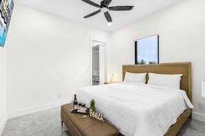 Ein Schlafzimmer mit Bett, Deckenventilator, Nachttisch und Fenster.