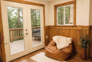 Ein Zimmer mit einer Schiebetür und Zugang zu einer Terrassenanlage, einer Holzbank und einem Fenster mit Vorhang.