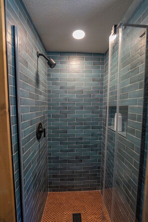 Eine Dusche mit blauen Fliesen und einer Glastür.