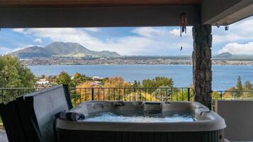 Ein Whirlpool auf einem Balkon mit Blick auf einen See und Berge.