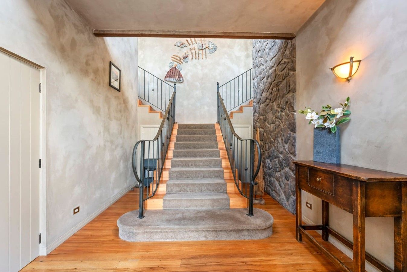 A staircase with a stone wall on one side and a wooden floor leading to a door.