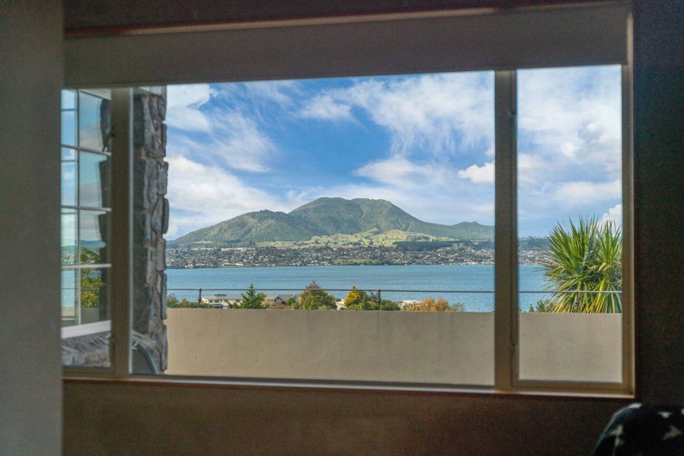 A window view of a coastal landscape with mountains and a body of water.