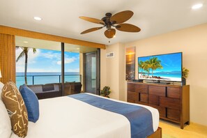Ein Hotelzimmer mit Bett, Fernseher, Deckenventilator und Meerblick.