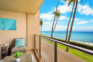 A balcony with a view of the ocean, a sofa, a small table, and a potted plant. - Beautiful 1BR Oceanfront Retreat in Kaanapali (Lahaina)
