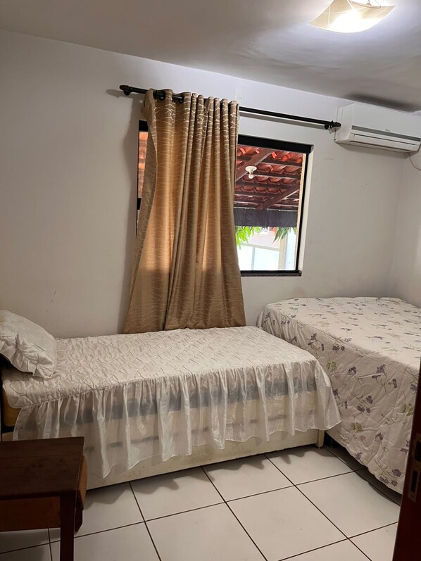 A room with two beds, a window with a view, and an air conditioning unit.