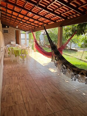 A covered patio with wooden flooring, a hammock, and outdoor seating. - House in a Gated Community - Caldas Novas, Goiás (Caldas Novas)