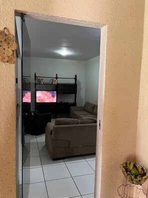 Uma sala de estar com sofá, televisão e estante.