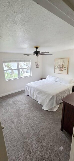 A bedroom with a bed, a ceiling fan, a window, and a door. - Private Pool Oasis | 3BR Home Near Busch Gardens (Tampa)