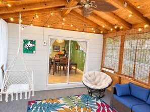 A room with a ceiling fan, string lights, a hammock chair, a cushioned chair, a blue sofa, and a patterned rug. - Private Pool Oasis | 3BR Home Near Busch Gardens (Tampa)